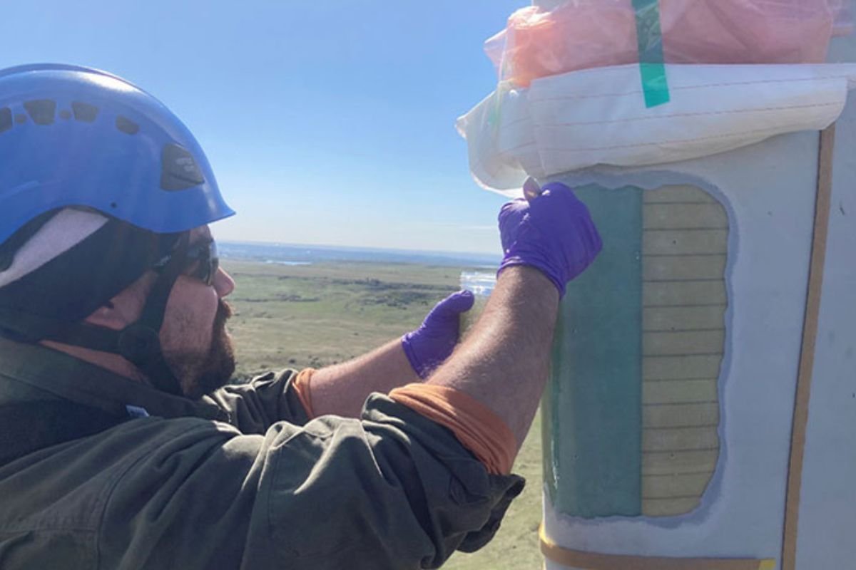 Once pressure belts were removed, NREL researchers David Barnes (above) and Ryan Beach and lead technician Mark Iverson set to work filling tiny holes in the leading edge of the blade left behind when the device’s flyboards were removed. Image by Ryan Beach, NREL